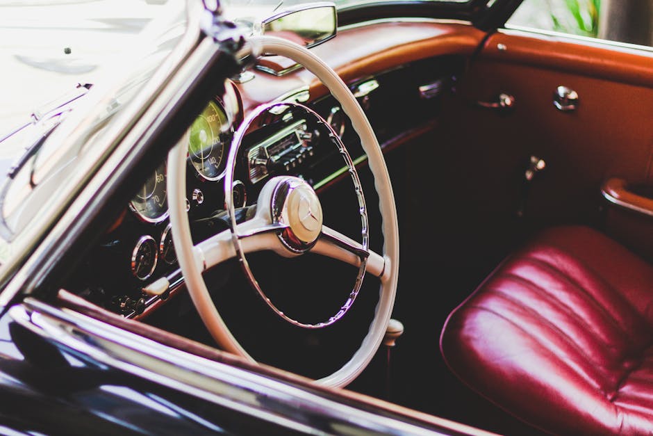A vintage luxury car interior featuring stylish chrome details and red leather seats.