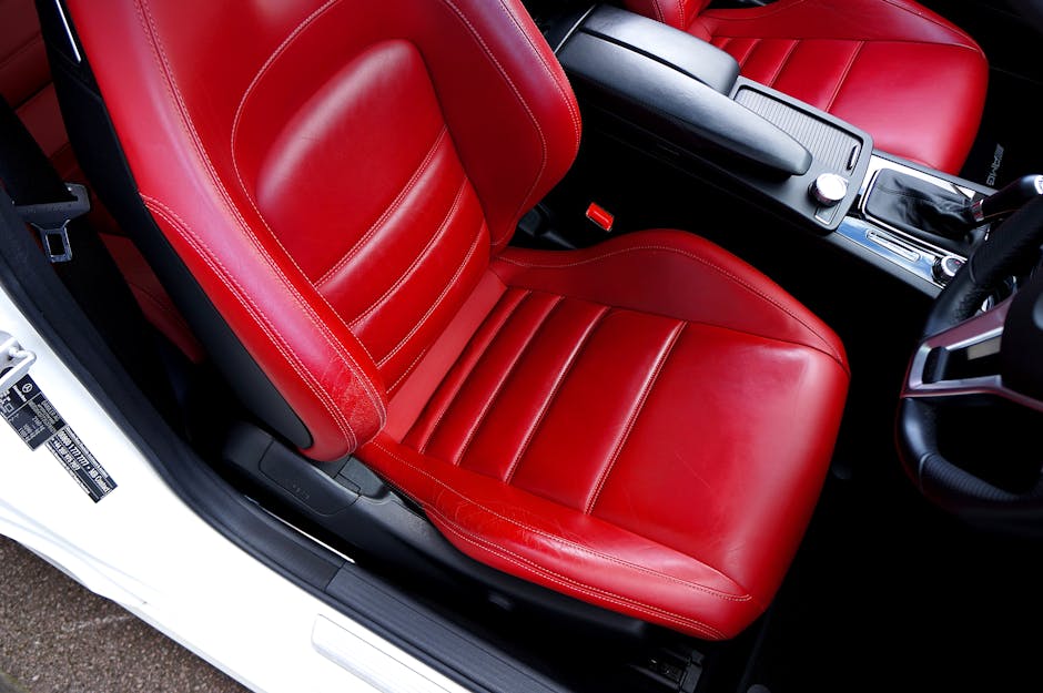 A detailed view of a red leather car seat in a modern car's interior, showcasing luxury and style.